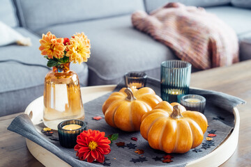 Autumn, fall cozy mood composition for hygge home decor. Small pumpkins, burning candles and fresh...