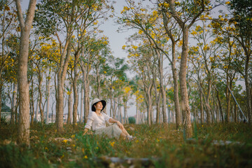 woman sitting through a park full of trees at sunset