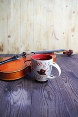 still life of cup of coffee and violin on wooden background