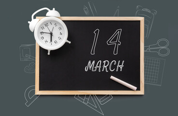 march 14. 14th day of month, calendar date. Blackboard with piece of chalk and white alarm clock on green background. Concept of day of year, time planner, spring month