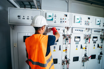 Adult electrician builder engineer testing and screwing equipment in fuse box and repairing of modern electricity power station using voltmeter. Automatic control cabinet