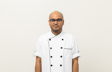 Smiling Young handsome asian man chef in uniform with glasses standing posting looking at camera on isolated background. Cooking man Occupation chef or baker People in kitchen restaurant and hotel.