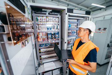 Adult electrician builder engineer testing and screwing equipment in fuse box and repairing of...