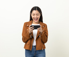 Fototapeta premium Excited Beautiful young asian women play mobile game and standing on isolated yellow background. Playing game on smartphone winning victory moment. Very enjoy and fun relax time