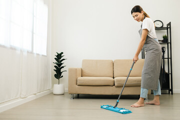 Young beautiful woman with apron and rubber glove with mop ready for cleaning home. Housekeeping housework or maid worker holding mop cleaning floor