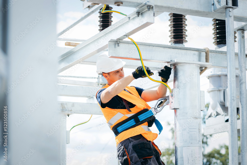 Wall mural electrician in protective helmet working on high voltage power lines. highly skilled workmen servici