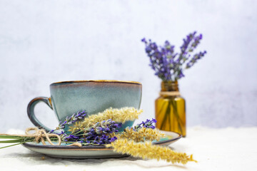 Cup of hot aromatic tea with a bouquet of natural lavender on a gray background.