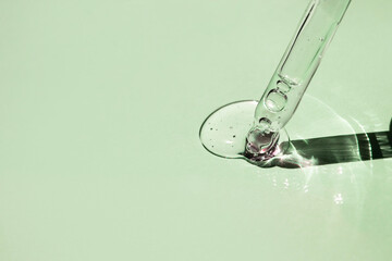 Aloe vera gel and a glass pipette on a pale green background. Side view, space for text.