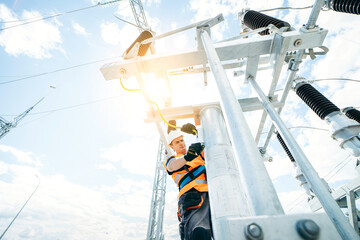 Electrician in protective helmet working on high voltage power lines. Highly skilled workmen...
