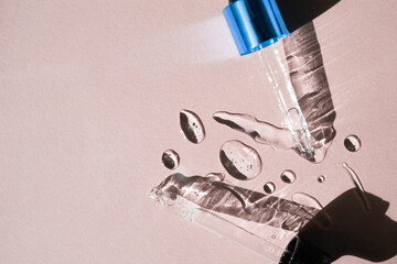 Drops of gel-like cosmetic liquid and glass pipettes on a beige background. Top view, place for...