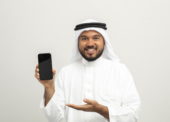Portrait of arabic man with kandura dress using cellphone on isolated white background. Arab...