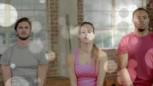 Animation of lens flares over multiracial friends exercising with kettlebells in gym