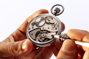 Closeup watchmaker's hands repairing mechanical watches isolated over white background. Concept of...