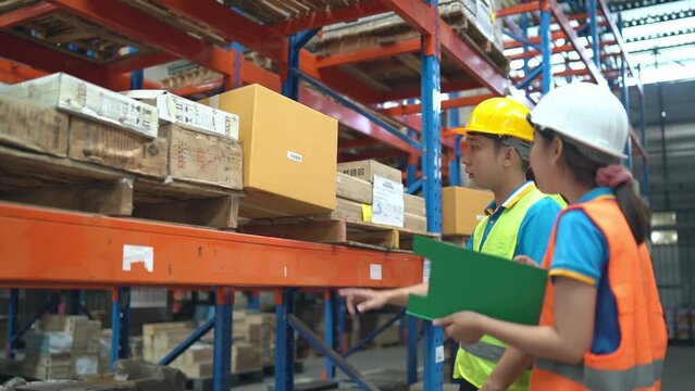 Young Asian worker using barcode scanner checking goods and box shelf stock in the warehouse factory store, co-worker man counting check stock. Warehouse Logistic concept.