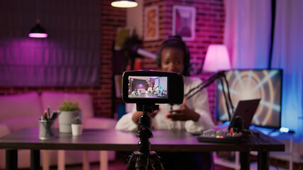 Selective focus on digital video camera screen recording african american vlogger talking to audience from home podcasting studio. Influencer filming herself doing live broadcast for social media.