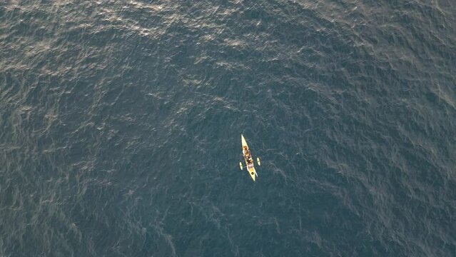 Yellow kayak is fihing at the middle of the ocean. Aerial top down static shot.