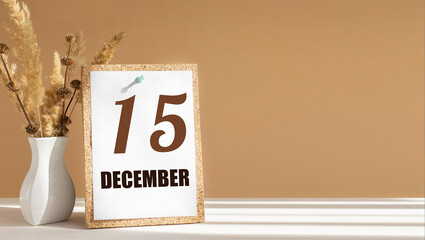december 15. 15th day of month, calendar date.White vase with dead wood next to cork board with numbers. White-beige background with striped shadow. Concept of day of year, time planner, winter month