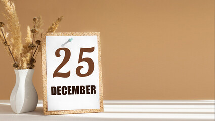 december 25. 25th day of month, calendar date.White vase with dead wood next to cork board with numbers. White-beige background with striped shadow. Concept of day of year, time planner, winter month