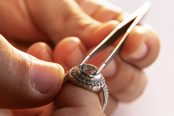 Working process. Closeup hands of jeweler at work in jewelry. Desktop for craft jewelry making with professional tools. - obrazy, fototapety, plakaty