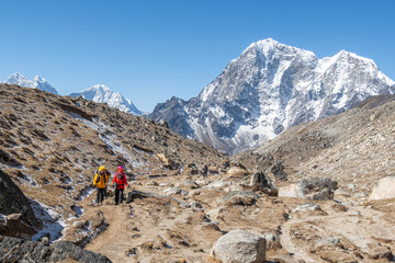 Fototapeta premium Tourist and porters walking on dirt road in Nepal to Everest Base Camp. Khumbu Glacier, way to Mt Everest base camp, Khumbu valley, Sagarmatha national park, Nepal