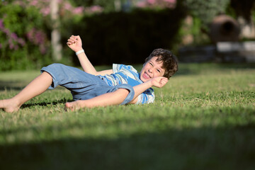 Fototapeta premium boy preschooler somersaults on the grass on a hot summer day.