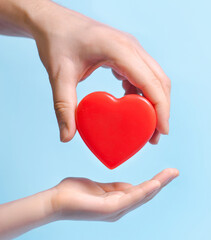 Hand person giving a heart to another person on blue background.Poster, banner, copy space for text