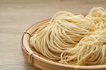 raw ramen noodle in wood plate on wooden table background. fresh egg ramen noodles and wooden...