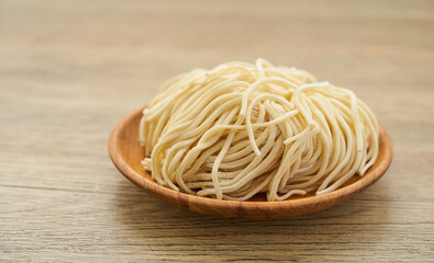 raw ramen noodle in wood plate on wooden table background. fresh egg ramen noodles and wooden background.                                  