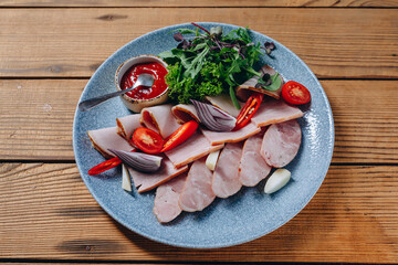There is a blue plate of sausages on the wooden table of the restaurant.