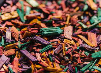 Textured background of decorative colored sawdust for finishing flower beds. Green, burgundy, yellow, red and purple sawdust. The texture of small colored wood chips.