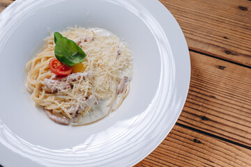 There are a long plate of paste and cheese on the wooden table of the restaurant.