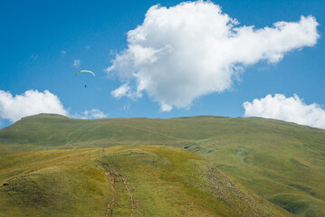 Un parapente dans les Alpes. Un parapentiste au dessus d'une montagne. Un parapente dans un ciel bleu avec un nuage blanc.