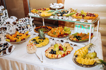 Buffet table with sliced ​​fruits and sweets.