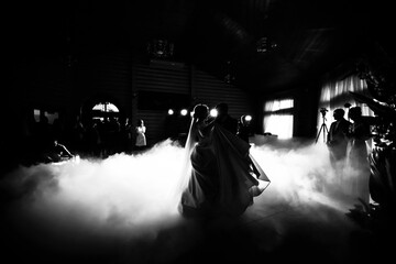 Black and white photo of the first dance of newlyweds with lighting effects and confetti,...