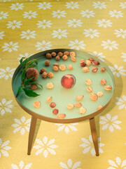 Peaches and many peach seeds of already eaten fruits on a blue round table standing on a yellow carpet as a sign that the peaches are so delicious