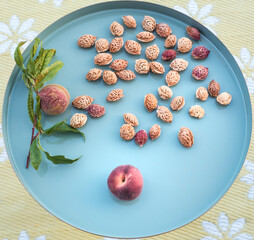 Peaches and many peach seeds of already eaten fruits on a blue round table standing on a yellow carpet as a sign that the peaches are so delicious