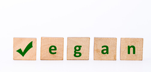 The word vegan on isolated wooden stones written in green letters with white background