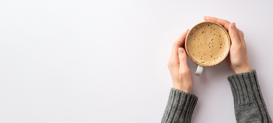 Autumn mood concept. Panoramic first person top view photo of girl's hands in grey pullover holding mug of frothy coffee on isolated white background with copyspace