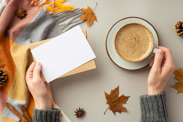 First person top view photo of female hands in jumper holding envelope paper card cup of coffee on...