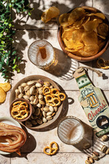 Outdoor beer party concept with beer in glasses, snacks chips, nuts, pretzels on tile background, top view