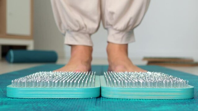 A woman stands on a sadhu board. Side view. Blue wooden board for meditation and soul harmonization. Take the first step in the practice of sadhu yoga