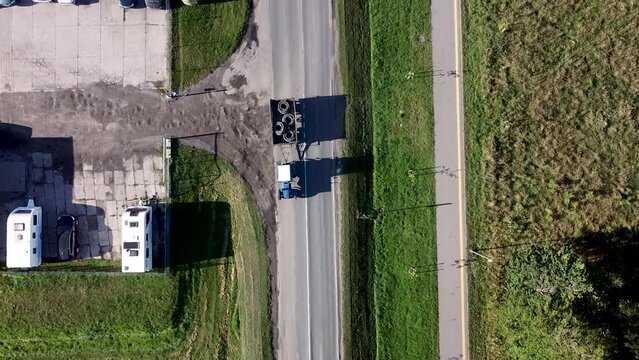 Arial drone shot of cars passing local business entrance. Trailer park and car park. Lithuania.