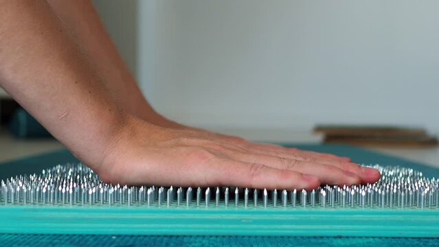 The woman puts her hands on the sadhu board. Side view. Turquoise wooden board for meditation and soul harmonization. Take the first step in the practice of sadhu yoga