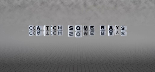 catch some rays word or concept represented by black and white letter cubes on a grey horizon...