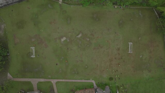 Top down aerial footage of a group playing soccer in a field.