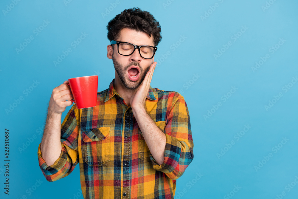 Poster Photo of sleeping brunet guy drink tea wear spectacles plaid shirt isolated on blue color background