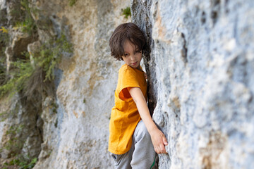 A little rock climber is training to climb a boulder