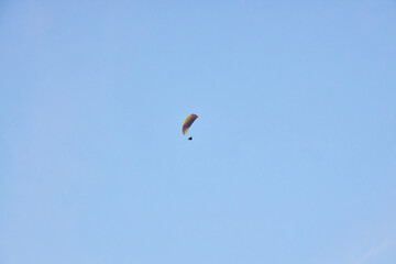 Paraglider silhouette flying in the blue sky.