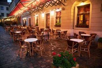 tables and chairs of a street restaurant in evening - 523511476