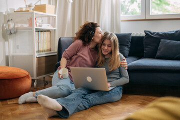 mother and daughter using laptop computer sitting in living room